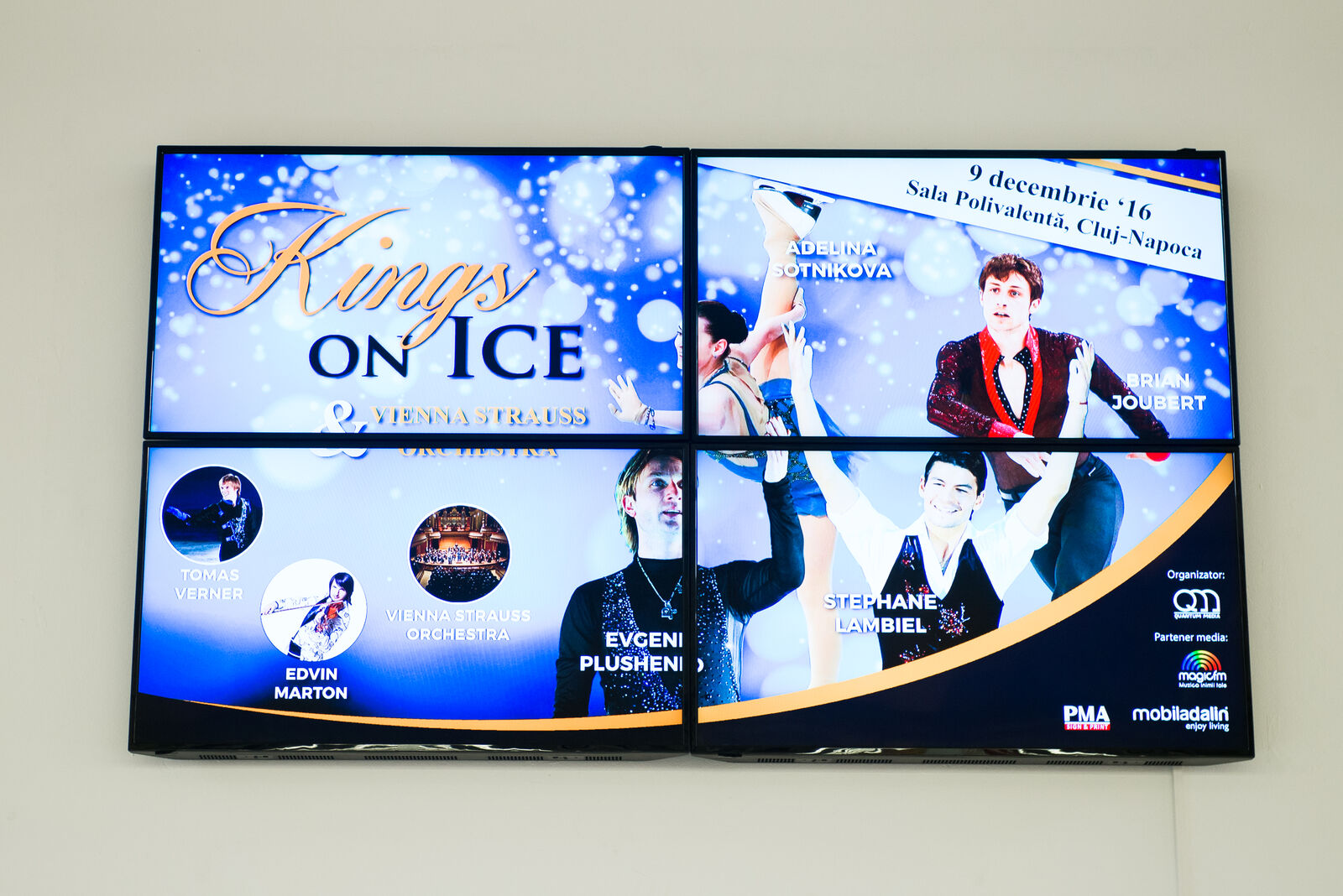 A tiled video wall drives a vivid winter-show promotion as one large image in a mall foyer.
