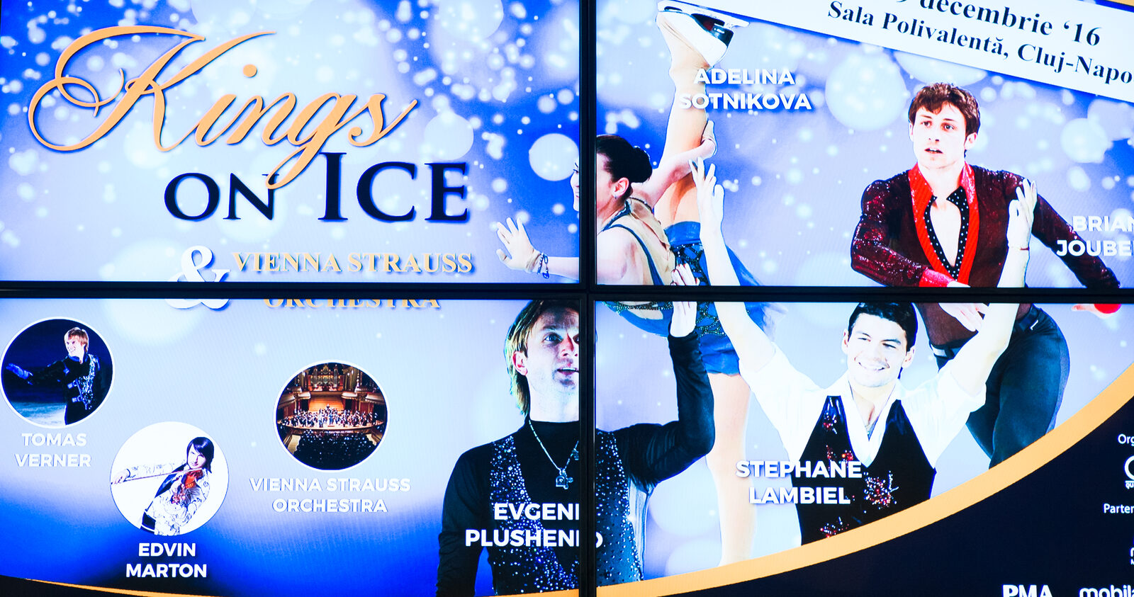 A tiled video wall in a mall foyer shows one event campaign across four synced panels.